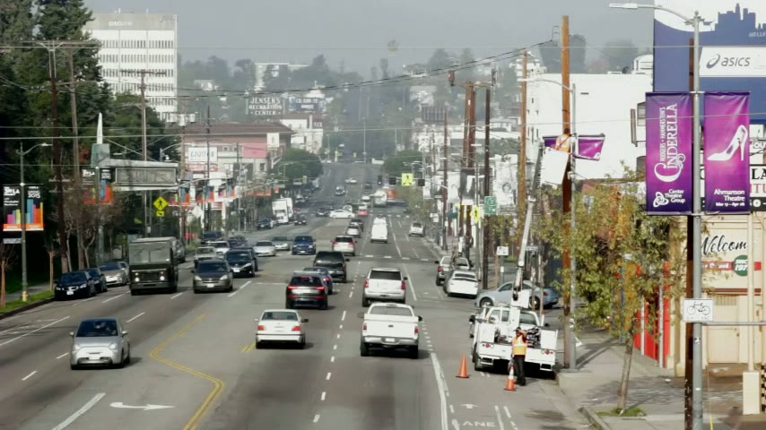 Pole banners being installed along a busy Los Angeles boulevard